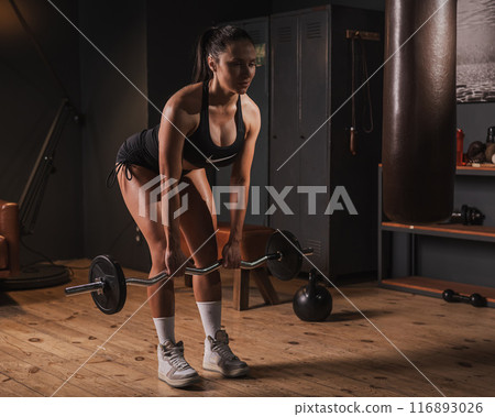 Caucasian woman doing deadlifts in retro gym.  116893026