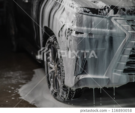 Foam drips from the bumper of a black car. Car wash.  116893058