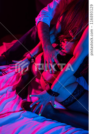 A man hugs a woman handcuffed by the buttocks. BDSM concept. Vertical photo. A man hugs a woman handcuffed by the buttocks. BDSM concept. Vertical photo. 116893129