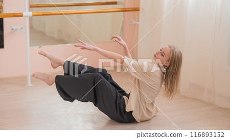 Caucasian woman dancing contemporary on the floor in a ballet class.  116893152