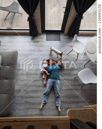 Top view of caucasian woman lying on floor with son and jack russell terrier dog. Vertical photo.  116893278