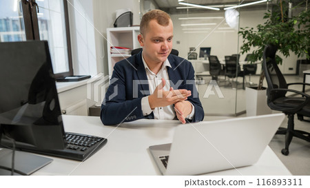 Caucasian deaf man talking sign language over video call on laptop in office. Caucasian deaf man talking sign language over video call on laptop in office. 116893311