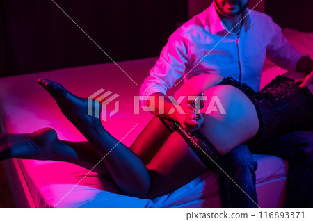 A man with a mistress on his knees holds an anal plug in the bedroom. A man with a mistress on his knees holds an anal plug in the bedroom. 116893371