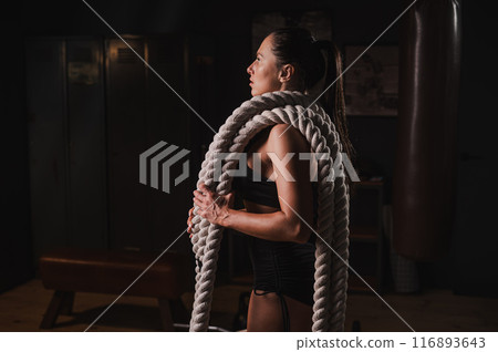 Caucasian woman posing with ropes in retro gym. Caucasian woman posing with ropes in retro gym. 116893643
