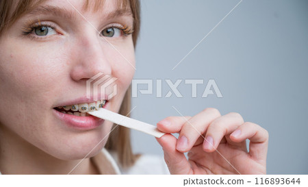 Young woman with metal braces on her teeth is chewing gum. The girl is eating gummy candy Young woman with metal braces on her teeth is chewing gum. The girl is eating gummy candy 116893644