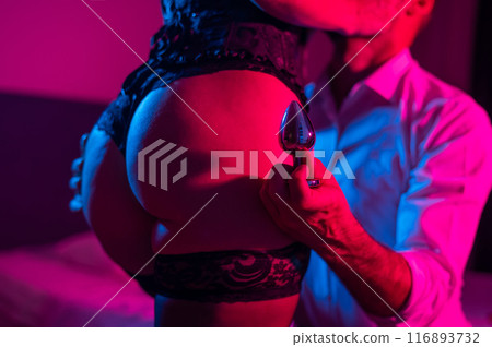 The man is holding an anal plug. Close-up of female buttocks in underwear. Sexual preferences of the couple. 116893732