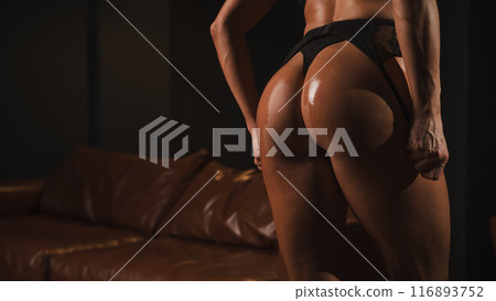 Close-up of a woman's tanned athletic buttocks oiled up. Close-up of a woman's tanned athletic buttocks oiled up. 116893752