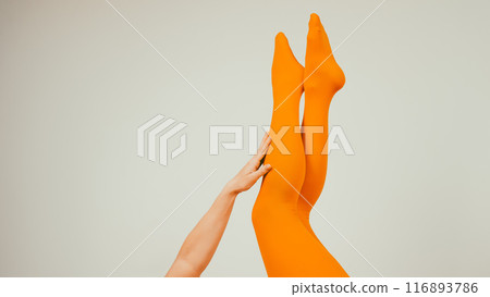 Female legs in ocher tights on a white background. Copy space.  116893786
