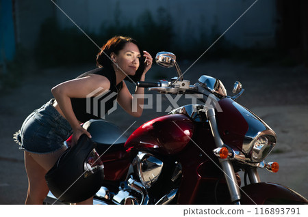 Brunette woman looks in the rearview mirror on a motorcycle. Brunette woman looks in the rearview mirror on a motorcycle. 116893791