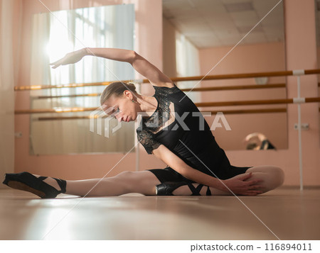 Woman in pointe shoes sits on the floor and does ballet warm-up. Woman in pointe shoes sits on the floor and does ballet warm-up. 116894011