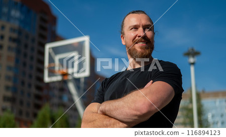 Portrait of a Caucasian bearded man on a basketball court outdoors.  116894123