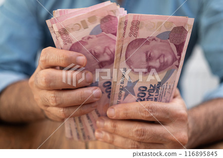 Male tourist holds Turkish lira banknotes in hands counting money after currency exchange procedure with favorable rates sitting at desk in local bank Male tourist holds Turkish lira banknotes in hands counting money after currency exchange procedure with favorable rates sitting at desk in local bank 116895845