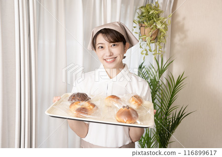 Female bakery staff holding freshly baked bread 116899617