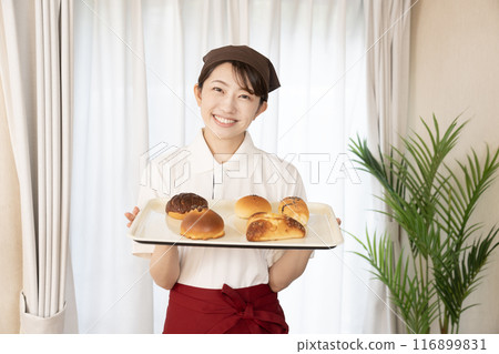 Female bakery staff holding freshly baked bread Female bakery staff holding freshly baked bread 116899831
