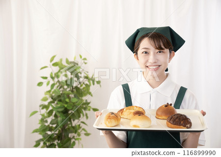Female bakery staff holding freshly baked bread Female bakery staff holding freshly baked bread 116899990