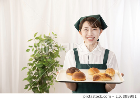 Female bakery staff holding freshly baked bread Female bakery staff holding freshly baked bread 116899991