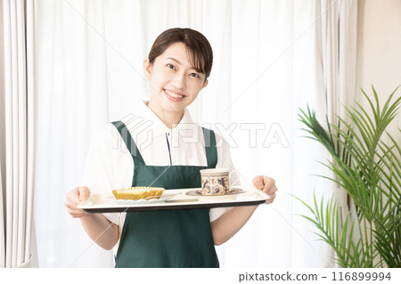 女咖啡館員工微笑著端著咖啡和蛋糕 女咖啡館員工微笑著端著咖啡和蛋糕 116899994