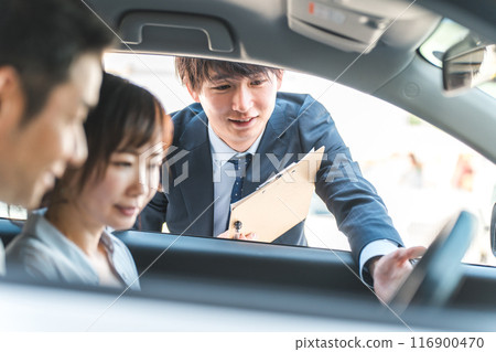 A young Asian male salesman serving customers who came to buy, assess and purchase a car 116900470
