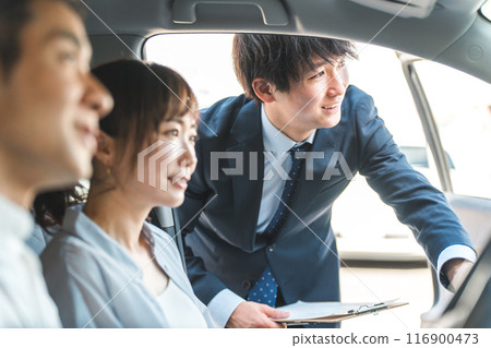 一位年輕的亞裔男性推銷員為前來選購、估價、購車的顧客服務。 一位年輕的亞裔男性推銷員為前來選購、估價、購車的顧客服務。 116900473