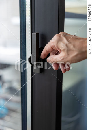 A man's hand touching the crescent (lever) of an insulated sash 116900796