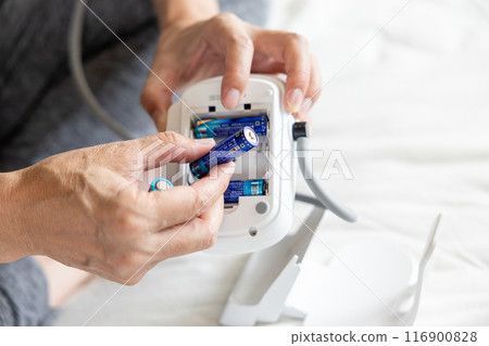 A man changing the battery in a blood pressure monitor 116900828