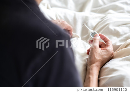 一個男人觸摸床上的溫度計 116901120