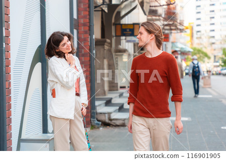 Young Caucasian woman looks at handsome smiling young man passing by on street. Psychology of relationship Young Caucasian woman looks at handsome smiling young man passing by on street. Psychology of relationship 116901905