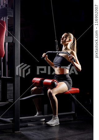 Woman Performing Lat Pulldown Exercise on a Cable Machine in a Gym 116902007