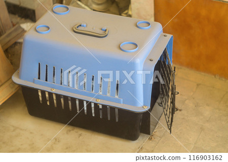 Empty carrier bag for safe transfer of pet cats in black color with the door open. Dusty due to non-use. Devices for tourism, moving pets. Empty carrier bag for safe transfer of pet cats in black color with the door open. Dusty due to non-use. Devices for tourism, moving pets. 116903162