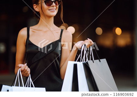 Shopping bags in the hands. Fashion woman with packages after shopping. Black friday, sale. Shopping bags in the hands. Fashion woman with packages after shopping. Black friday, sale. 116903692