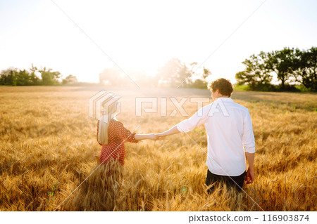Young happy couple hugging on a wheat field, on the sunset. Enjoying time together. Young happy couple hugging on a wheat field, on the sunset. Enjoying time together. 116903874