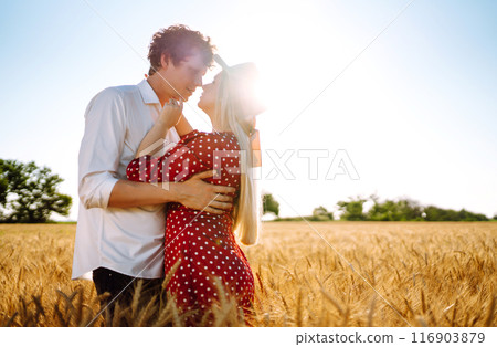 Young happy couple hugging on a wheat field, on the sunset. Enjoying time together. Young happy couple hugging on a wheat field, on the sunset. Enjoying time together. 116903879