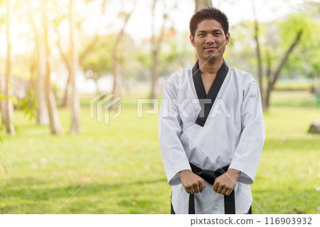 Asian Taekwondo male fighter standing practise in nature park garden outdoor happy smile 116903932