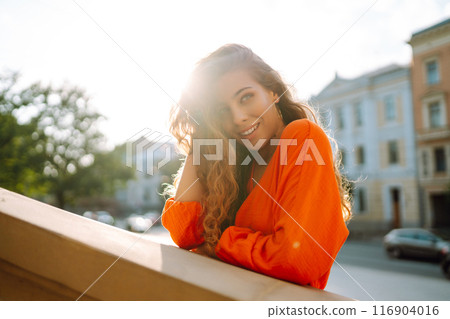 Female tourist in bright dress enjoys sights of the city on sunny day. Concept of lifestyle, fashion 116904016