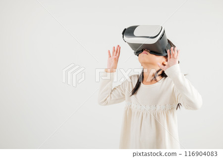 Portrait Asian smiling kid girl touching at something in a virtual reality glasses headset studio shot isolated white background, Excited happy kindergarten child using VR play simulation game Portrait Asian smiling kid girl touching at something in a virtual reality glasses headset studio shot isolated white background, Excited happy kindergarten child using VR play simulation game 116904083