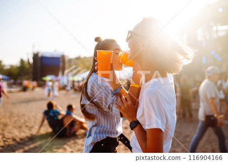 Two woman having great time at music festival. Girlfriends rinking beer at Beach party. Lifestyle. 116904166