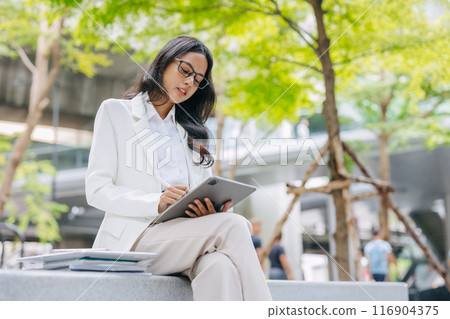 Business Young people. Asian Indian working women smart girl with tablet green park outdoor. 116904375