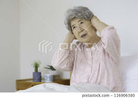 Senior woman holding her head in the bedroom Senior woman holding her head in the bedroom 116906380