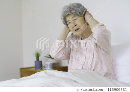Senior woman holding her head in the bedroom Senior woman holding her head in the bedroom 116906381