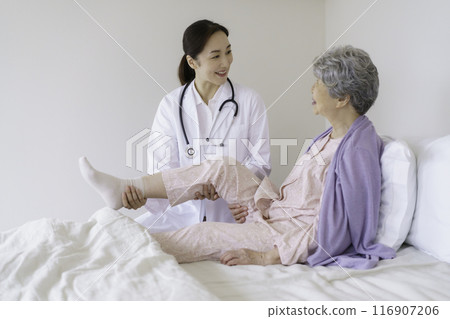 女醫生在臥室檢查膝蓋的高級婦女 女醫生在臥室檢查膝蓋的高級婦女 116907206