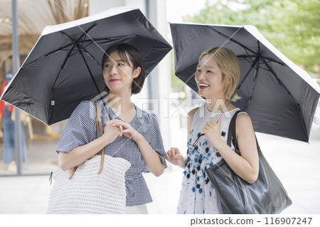 two women holding parasols 116907247
