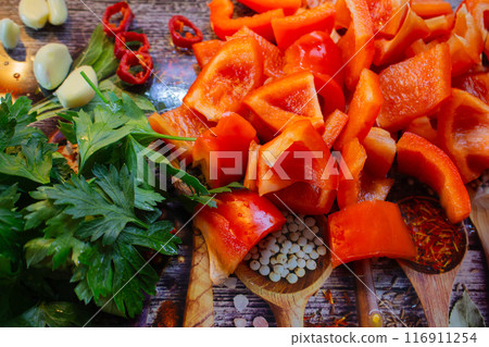 Vegetables and herbs on cutting board. Sliced tomato, bell pepper, chilli pepper, garlic and parsley on the table. Summer salad ingredients. Healthy eating. Organic food background. 116911254