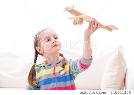 Beatiful smiley girl playing with old-fashioned wooden toy plane 116911299