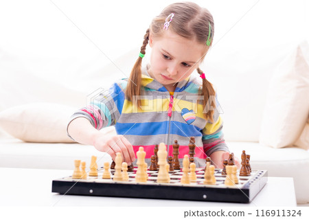 Cute small girl is hardly concentrated, when plating chess game 116911324
