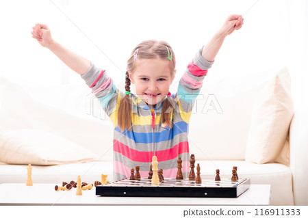 Adorable school age girl feels extremely happy about winning in chess 116911333