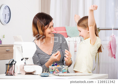 mother and daughter sew clothes in the workshop 116911342
