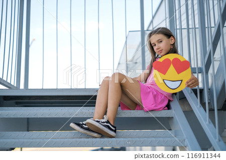 The girl demonstrates love by transmitting through emoticons. Smile face with hearts 116911344