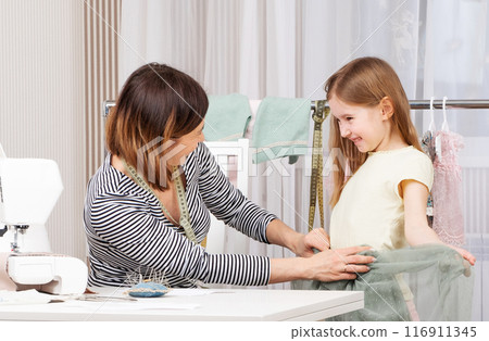 mother and daughter sew clothes in the workshop 116911345