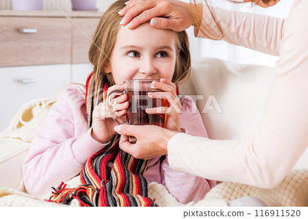 Little ill girl in scarf drinking tea 116911520