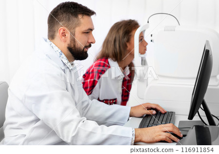 Teenage girl udergoes eye survey with doctor on tomograph in ophthalmologic clinic Teenage girl udergoes eye survey with doctor on tomograph in ophthalmologic clinic 116911854